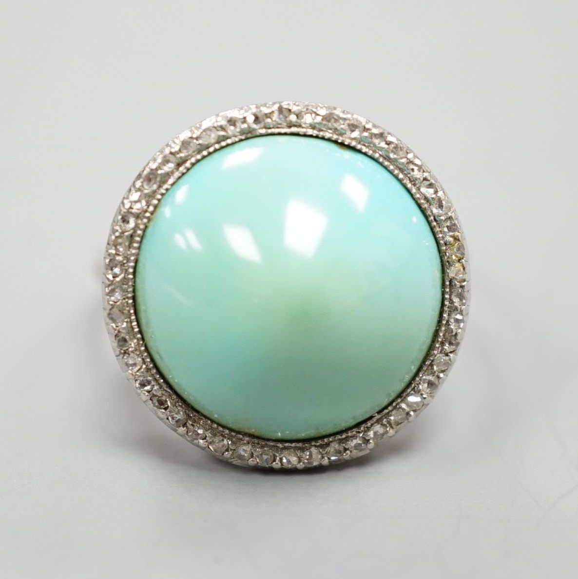 A white metal cabochon turquoise and diamond chip set dress ring, size J/K, gross 6.9 grams.